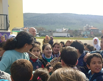 A friend sings with the kids at the school, I’m in the background and the hills of Syria in the background.